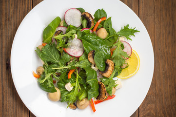 Fresh spring salad with radish, Mizuno, mushrooms grilled, Adygei cheese, spinach, bell pepper, lemon, corn. Wooden background