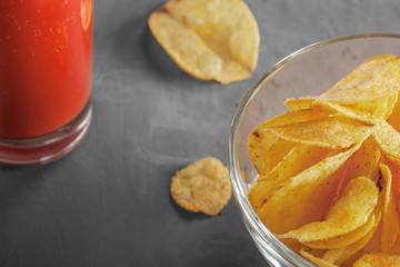 Potato chips in bowl with tomato juice in glass