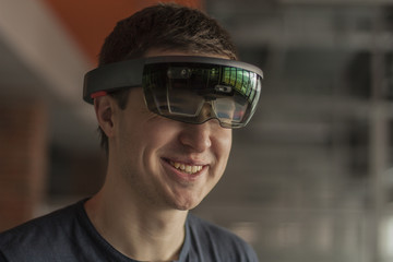 Young man wearing virtual reality goggles. Headset. Glasses with virtual screen. Man touch something using modern glasses with virtual screen. Device.  Man playing game.