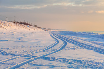 Perspective view of snowy poles in the sunset time. Coast of Baltic Sea.