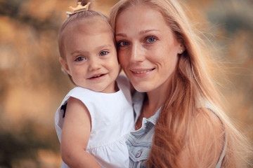 Mom holding daughter in her arms autumn photos in yellow park