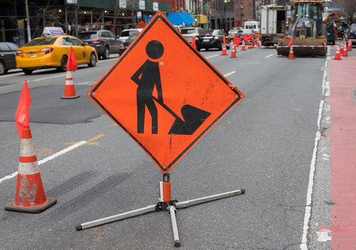 Orange Construction Sign Of Man With Shovel On City Street