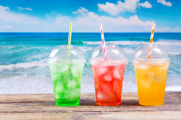 colorful cold drinks in plastic cups on the beach