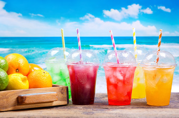 colorful cold drinks in plastic cups on the beach
