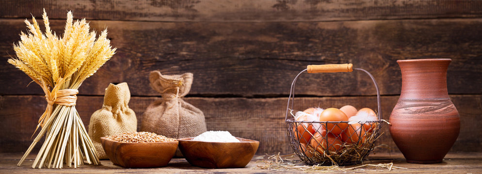 wheat ears with bowl of grains, flour, milk and eggs