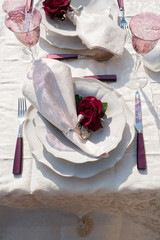 Romantic table setting with rose champagne glassess, white plates and napkin rings with roses.