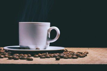 Cup of hot coffee and saucer on a brown table. Dark background.