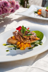 Foie gras with apricot-chili salsa, pak choi and sweet chili. On white plate and restaurant table.