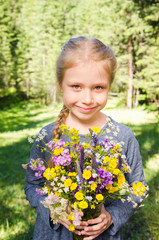 Little girl on meadow with a bouquet of wild flowers