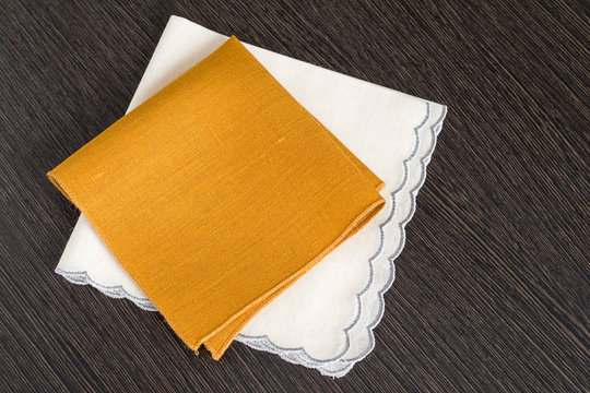 
Two handkerchiefs .   Two handkerchiefs of cotton fabric with  treated the edges on a dark wooden background.