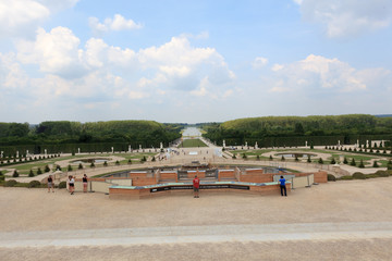 Fototapeta na wymiar The huge park surrounding the Palace of Versailles with beautiful fountains, flowers and symmetrical flower beds and hedges.