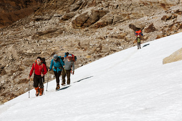 Group of Climbers walking on Snow Nepalese Porter on Background