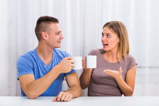 Young happy couple enjoys drinking coffee,talking and laughing together.
