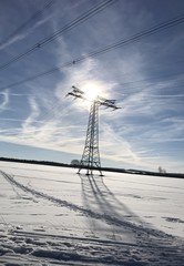 Winterlandschaft mit Schnee bei strahlendem Sonnenschein - Strommast mit Loipe