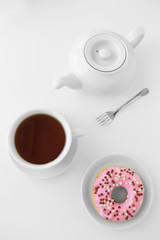 Delicious donut with cup of tea on white background