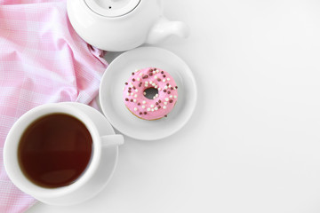 Delicious donuts with cup of tea on white background