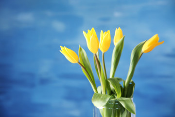 Glass vase with bouquet of beautiful tulips on color background