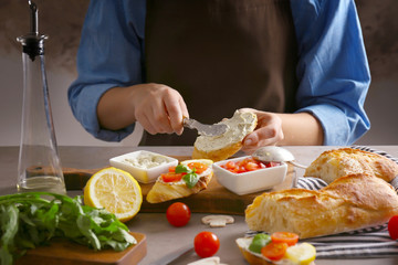 Woman making delicious traditional bruschetta on kitchen table