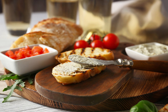 Tasty bruschetta with creamy cheese on wooden board