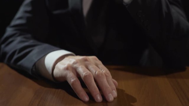 Thoughtful man tapping fingers on table while thinking about problem solution