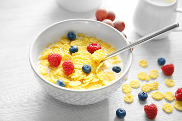 Tasty cornflakes with raspberries and blueberries on table