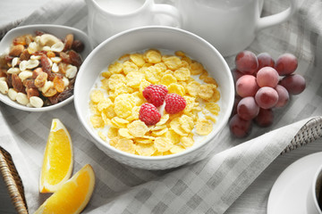 Tasty cornflakes with raspberries on table