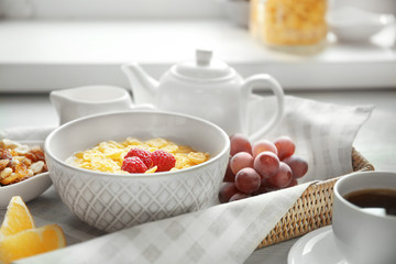 Tasty cornflakes with raspberries and cup of coffee on table