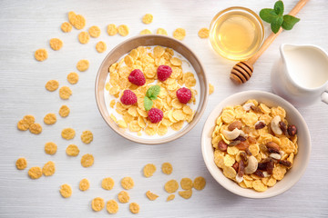 Tasty cornflakes with raspberries and honey on table