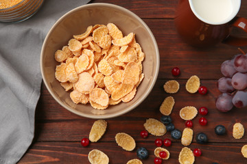 Tasty cornflakes with blueberries and redcurrant on wooden background