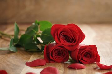 three red roses and petals on old wood table with copy space, romantic background