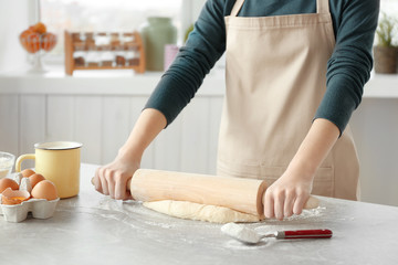 Woman preparing dough on table at kitchen