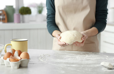 Woman preparing dough on table at kitchen