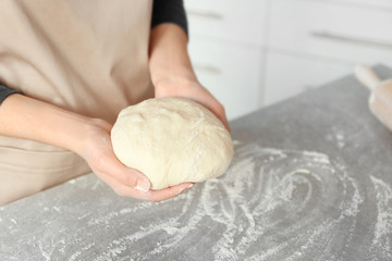 Woman preparing dough on table at kitchen