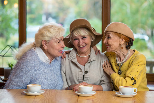Senior women at table smiling. Cheerful ladies in cafe. Friends since childhood.