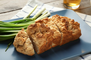 Plate with tasty loaf of beer bread on wooden background