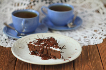  two cups of tea and a piece of chocolate cake on a table with a white lace tablecloth