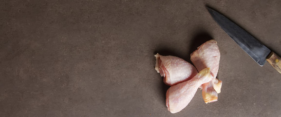 Chicken legs with a knife on a gray background. Lunch on the gri