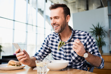 Man using smartphone while eating - Powered by Adobe