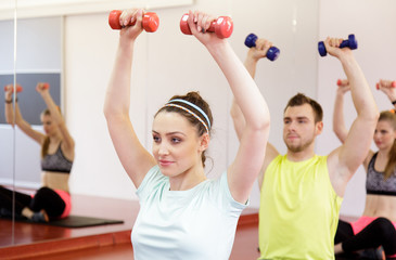 Young people working out with dumbbells in gym