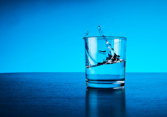 fresh clear blue water splash in glass