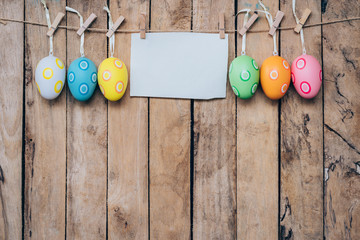 easter egg and blank paper for label hanging on wood background