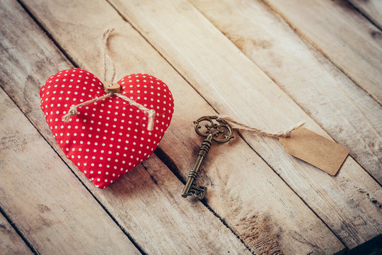 Heart fabric and vintage key with tag on wood table background.