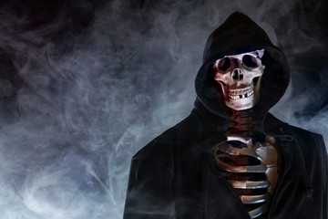 ein Skelett trägt einen Umhang mit Kapuze und ist in Rauch gehüllt