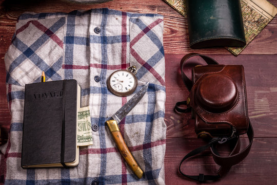 Des accessoires vintage de randonn&eacute;e  avec chemise &agrave; carreaux sur un fond de planches en bois 
