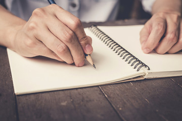 close up hand woman writing notebook on wood table background.