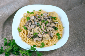 mushrooms of a veshanka and champignons in sauce with macaroni in a white plate on a table