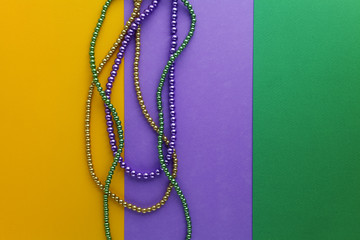 Multi color Mardi Gras beads on paper background. Top view