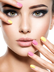Closeup face of beautiful woman with multicolored nails
