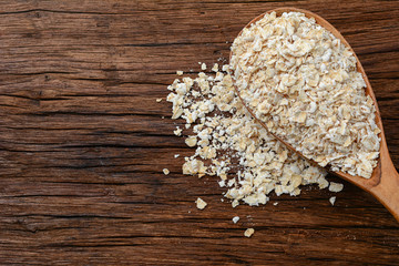 oat flakes on wooden spoon and on wooden table