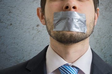 Censorship concept. Man is silenced with adhesive tape on his mouth.